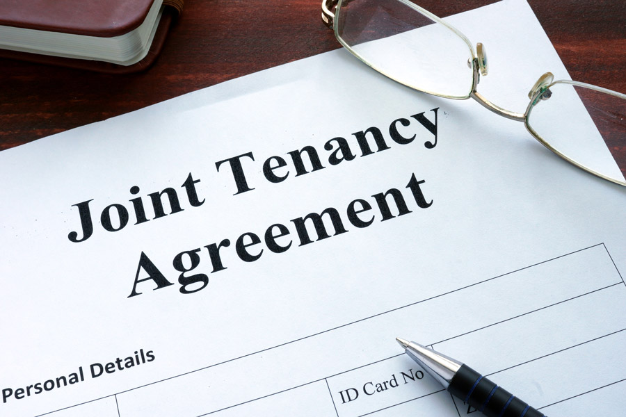 Joint Tenancy Agreement document with pen and glasses