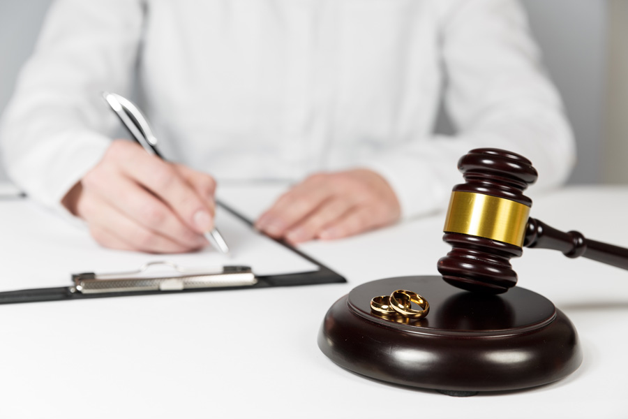 man signing paper with gavel and rings in front of him